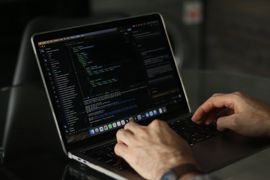 A close-up view of a laptop computer displaying a software development environment with code on the left side and a calculator interface with orange buttons on the right. The code is written in HTML a